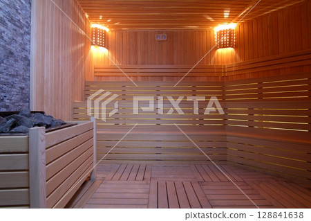 Seat in sauna room. Empty wooden steam room with stone heater.Sauna room for good health. Seat in sauna room. Empty wooden steam room with stone heater.Sauna room for good health. 128841638