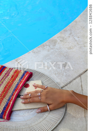 hand holding a book with a flower on the beach. beautiful woman reading a book by the pool. close-up. Blank book. 128841686