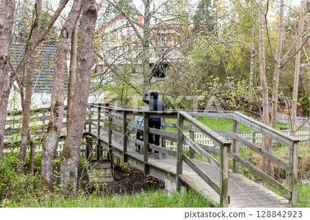 young Woman with Stroller Crossing Wooden Bridge on Rainy Spring Day young Woman with Stroller Crossing Wooden Bridge on Rainy Spring Day 128842923