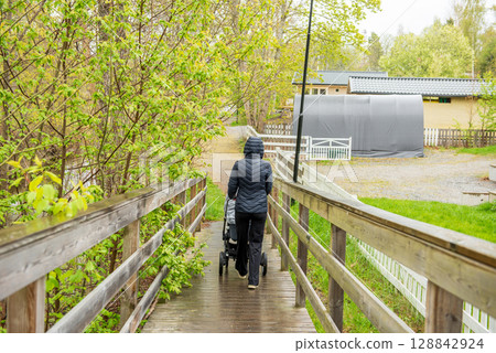 young Woman with Stroller Crossing Wooden Bridge on Rainy Spring Day young Woman with Stroller Crossing Wooden Bridge on Rainy Spring Day 128842924
