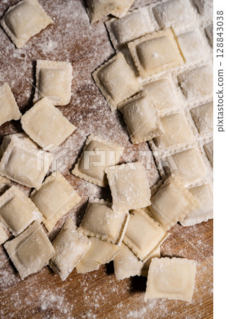 Fresh homemade uncooked ravioli pasta sprinkled with flour. Vertical Orientation Fresh homemade uncooked ravioli pasta sprinkled with flour. Vertical Orientation 128843038
