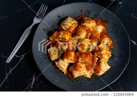 Ravioli pasta with tomato sauce and parsley on dark plate 128843064