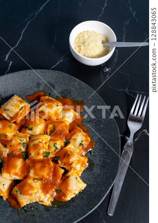 Ravioli pasta with tomato sauce and parsley on dark plate. Vertical Orientation Ravioli pasta with tomato sauce and parsley on dark plate. Vertical Orientation 128843065