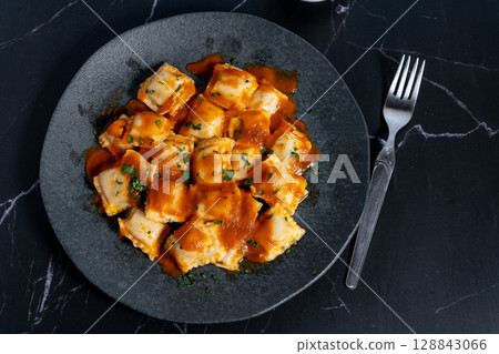 Ravioli pasta with tomato sauce and parsley on dark plate 128843066