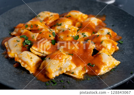 Ravioli pasta with tomato sauce and parsley on dark plate 128843067