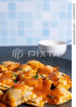 Ravioli pasta with tomato sauce and parsley on dark plate. Vertical Orientation 128843070