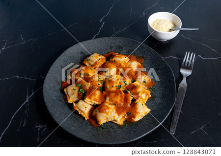 Ravioli pasta with tomato sauce and parsley on dark plate 128843071