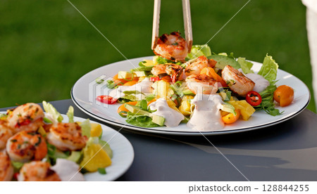 Chef put grilled shrimps on portion of freshly prepared healthy vegetable salad 128844255