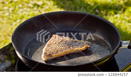 cook preparing fresh fish fillet on hot pan cook preparing fresh fish fillet on hot pan 128844257