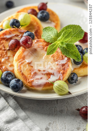 Cottage cheese pancakes with berries and condensed milk close up. Homemade dessert syrniki for healthy breakfast 128844287