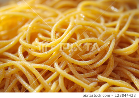 Close-up, appetizing view of freshly cooked, golden-yellow spaghetti noodles, showing their texture, inviting readiness, ideal as background, for illustrating recipes, Italian cuisine, simple food Close-up, appetizing view of freshly cooked, golden-yellow spaghetti noodles, showing their texture, inviting readiness, ideal as background, for illustrating recipes, Italian cuisine, simple food 128844428