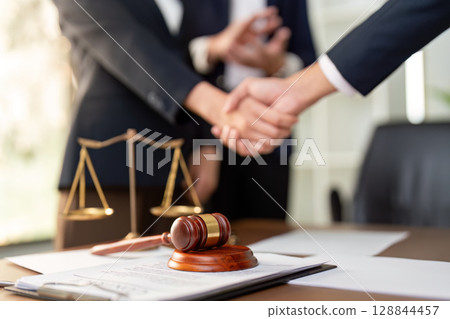 Handshake Over Legal Scales and Gavel in Office Handshake Over Legal Scales and Gavel in Office 128844457