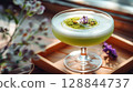 Botanical matcha cocktail with lilac syrup and dried flowers in glass goblet, soft shadows and natural autumn textures 128844737