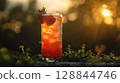 Colorful strawberry basil mocktail with herbs and ice in a tall glass, set outdoors with soft sunlight and casual summer feel 128844746