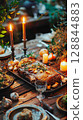 Traditional Slavic meal with glass of beverage, roast pork, vegetables and herbs on rustic wooden table in warm celebration light. 128844883