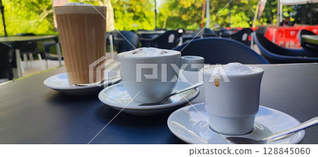Three different types of coffee - espresso, cappuccino and latte - served outdoors in a cafe in Portugal. The concept of coffee culture and drink themes in the country. Three different types of coffee - espresso, cappuccino and latte - served outdoors in a cafe in Portugal. The concept of coffee culture and drink themes in the country. 128845060