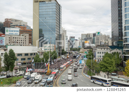 [South Korea] A view of a demonstration rally and cars and office buildings passing by on the main road from the pedestrian bridge in front of Seoul Station 128845265