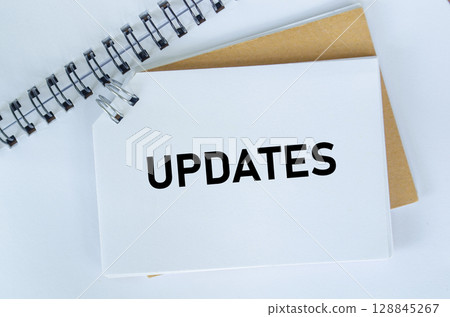 Top view of Updates text on white notepad. Business update concept Top view of Updates text on white notepad. Business update concept 128845267