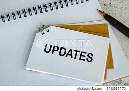 Top view of Updates text on white notepad. Business update concept. 128845272