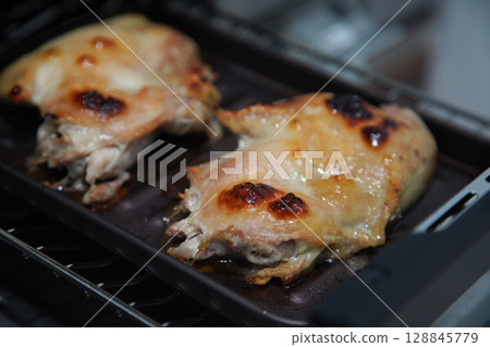 Grilling chicken thighs on a fish grill 128845779