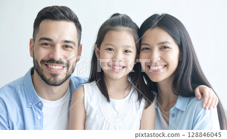 A photo that shows a happy family smiling and huddled together, with a warm bond centered around an adorable little girl 128846045
