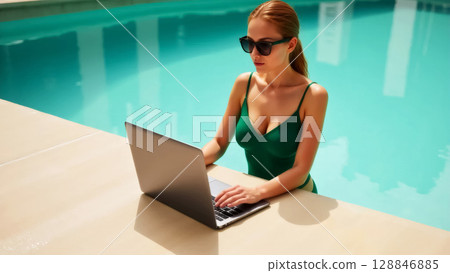 young beautiful woman in green swimsuit in swimming pool working on laptop, freelance concept 128846885