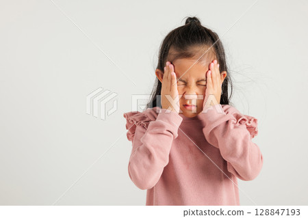 Portrait of Asian young kid girl sad tired strain face holding hold head by hands, stress kindergarten child person unhappy closed eyes problem headache, studio shot isolated on white background Portrait of Asian young kid girl sad tired strain face holding hold head by hands, stress kindergarten child person unhappy closed eyes problem headache, studio shot isolated on white background 128847193