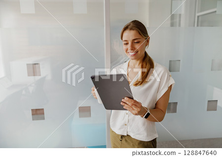 A Young Professional Engaging with a Tablet in a Modern Office Environment, Working Efficiently 128847640