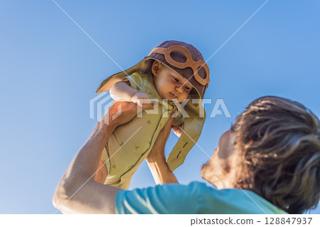 Father lifting baby in a pilot hat. Future pilot dream, aviation inspiration, and joyful family bonding concept. Sky is the limit Father lifting baby in a pilot hat. Future pilot dream, aviation inspiration, and joyful family bonding concept. Sky is the limit 128847937