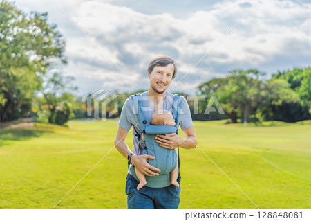 Young father walks in nature with his baby son nestled close in a parent-facing ergonomic baby carrier. Bonding, warmth, and modern parenting concept in a peaceful outdoor setting Young father walks in nature with his baby son nestled close in a parent-facing ergonomic baby carrier. Bonding, warmth, and modern parenting concept in a peaceful outdoor setting 128848081