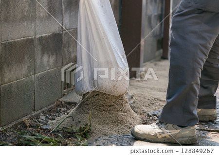Construction worker opening sandbags 128849267