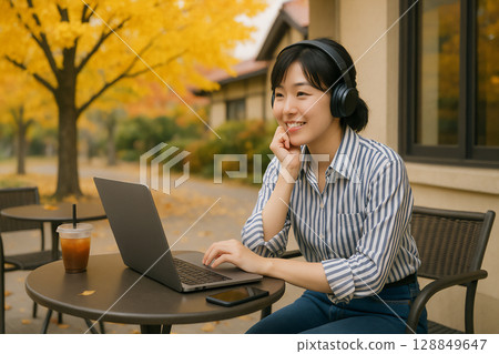 A woman using a laptop on a terrace at a cafe 128849647