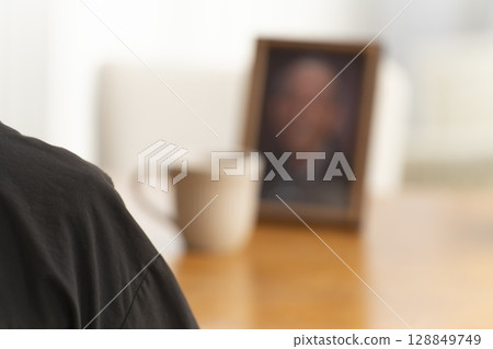 一位女士在客廳喝茶，同時看著丈夫的肖像 128849749