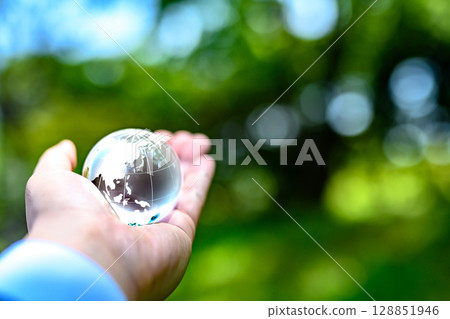 A crystal globe held up against beautiful fresh greenery Ecology image Earth black and white 128851946