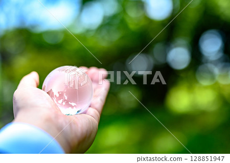 A crystal globe held up over beautiful new greenery - Ecology image - Normal color A crystal globe held up over beautiful new greenery - Ecology image - Normal color 128851947
