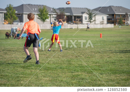 Kids engaging in flag football game at a community park during a sunny afternoon Kids engaging in flag football game at a community park during a sunny afternoon 128852380
