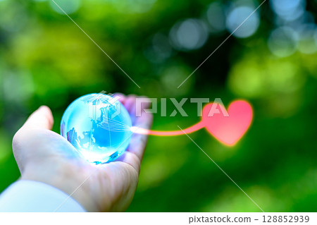 A crystal globe held up against beautiful fresh greenery. Hearts from Japan. Local power. Ecology image. Light blue. 128852939