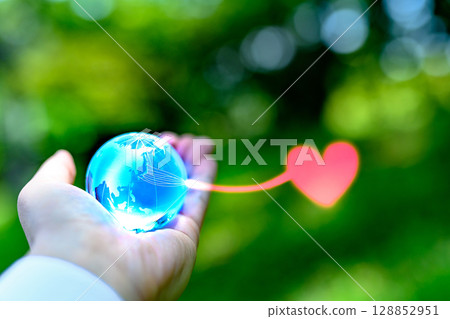 A crystal globe held up against beautiful fresh greenery. Hearts from Japan. Local power. Ecology image. Blue. 128852951