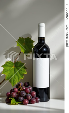 Clean minimalist wine concept featuring bottle, grapes, and green leaves, evoking sense of elegance and simplicity 128853505