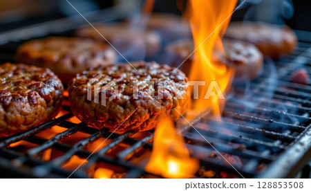 Grilled burger patties sizzling on barbecue with flames, creating delicious and smoky aroma 128853508