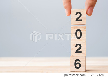 hand holding wooden cube block with 2026 text on table background. Resolution, plan, review, goal, start and New Year holiday concepts hand holding wooden cube block with 2026 text on table background. Resolution, plan, review, goal, start and New Year holiday concepts 128854289