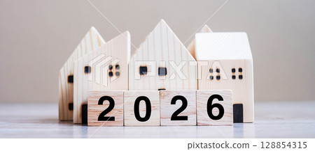 2026 Happy New Year with house model on table wooden background. Banking, real estate, investment, financial, savings and New Year Resolution concepts 128854315