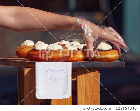 Hand Picking Homemade Pastry with Cream Filling at Open-Air Market 128854336