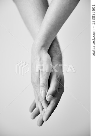 Close up view of hands of sweet couple. Young man and woman holding hands on light neutral background. Concept of love, intimacy, support, and trust. Black and white image. 128855601