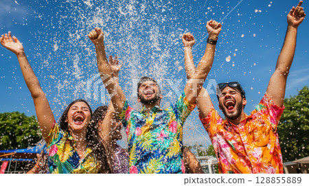 Joyful friends celebrating with splashes of water in vibrant shirts 128855889