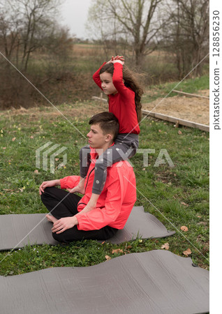 Kids enjoy playful yoga session in a serene outdoor setting while connecting with nature on a calm afternoon in the countryside Kids enjoy playful yoga session in a serene outdoor setting while connecting with nature on a calm afternoon in the countryside 128856230