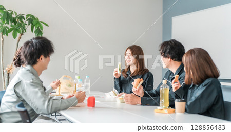 Businessmen and women in work clothes eating lunch in the break room 128856483