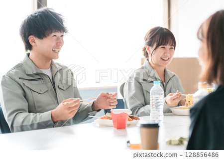Businessmen and women in work clothes eating lunch in the break room 128856486