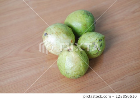 Four Ripe Guavas on Rustic Surface 128856610