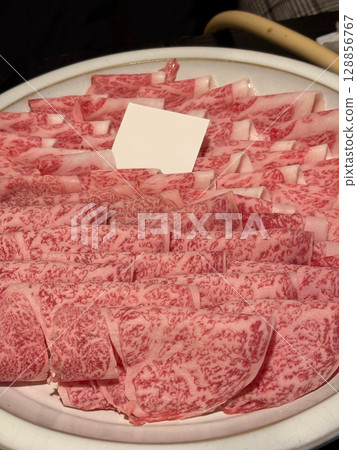 A plate with thinly sliced raw beef, ready to be used in shabu-shabu, sukiyaki or hot pot. A plate with thinly sliced raw beef, ready to be used in shabu-shabu, sukiyaki or hot pot. 128856767